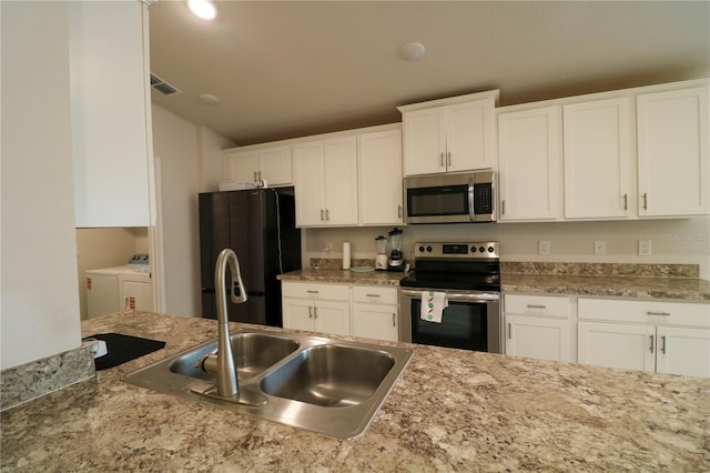 1105 Citrus Landings Blvd, Davenport, FL 33837 - kitchen with stainless steel appliances, washing machine and clothes dryer, white cabinets, and vaulted ceiling