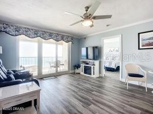2055 S Atlantic Ave Unit 505, Daytona Beach, FL 32118 - living area with wood finished floors, a ceiling fan, crown molding, and a fireplace