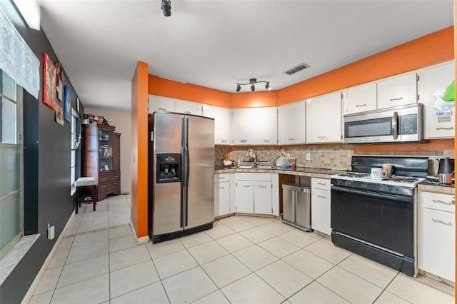 2309 Cilantro Dr, Orlando, FL 32837 - kitchen featuring stainless steel appliances, white cabinetry, decorative backsplash, and light tile patterned floors