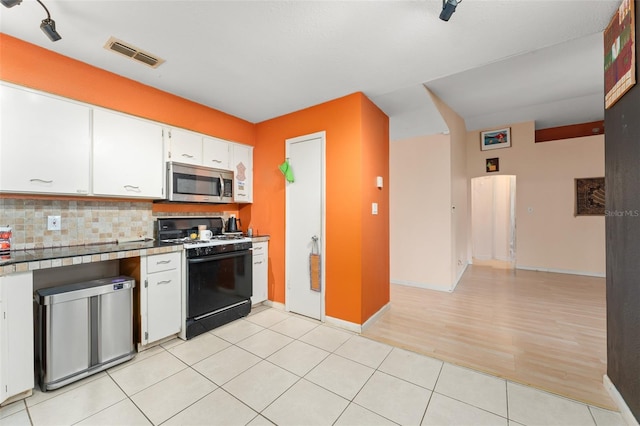 2309 Cilantro Dr, Orlando, FL 32837 - kitchen with gas range oven, stainless steel microwave, decorative backsplash, white cabinetry, and fridge
