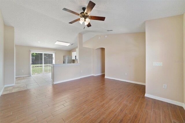 3313 Buckland St, Deltona, FL 32738 - unfurnished living room with a ceiling fan, light wood-type flooring, lofted ceiling, arched walkways, and a textured ceiling
