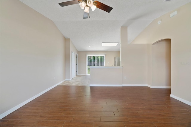 3313 Buckland St, Deltona, FL 32738 - empty room with wood finished floors, ceiling fan, vaulted ceiling, a textured ceiling, and arched walkways