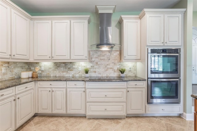 3531 Oriskany Dr, Orlando, FL 32820 - kitchen featuring stainless steel double oven, wall chimney range hood, black electric stovetop, dark stone countertops, and backsplash