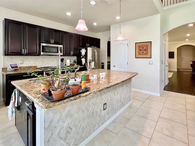 14654 Yellow Butterfly Rd, Windermere, FL 34786 - kitchen featuring arched walkways, appliances with stainless steel finishes, an island with sink, light tile patterned floors, and recessed lighting