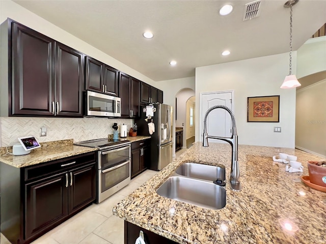 14654 Yellow Butterfly Rd, Windermere, FL 34786 - kitchen with appliances with stainless steel finishes, arched walkways, decorative backsplash, hanging light fixtures, and light stone countertops