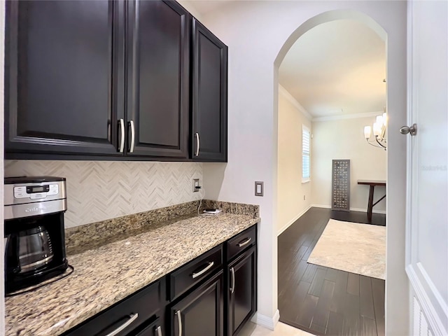 14654 Yellow Butterfly Rd, Windermere, FL 34786 - kitchen featuring arched walkways, decorative backsplash, crown molding, light stone counters, and light wood finished floors