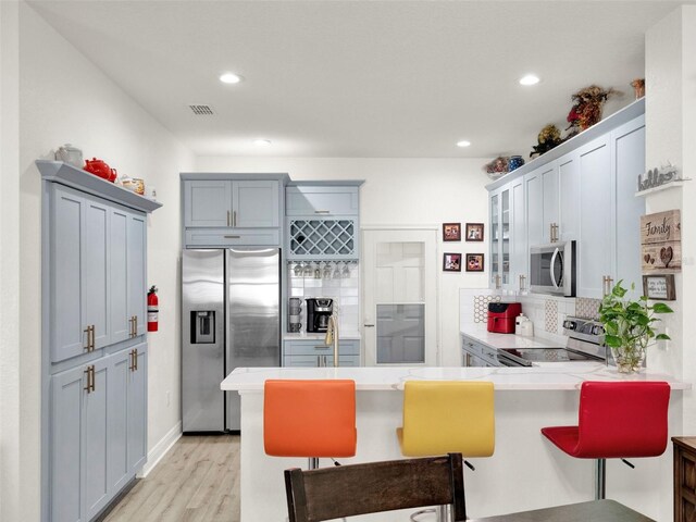 12347 NE 52nd Loop, Oxford, FL 34484 - kitchen with stainless steel appliances, a peninsula, light countertops, tasteful backsplash, and a kitchen breakfast bar