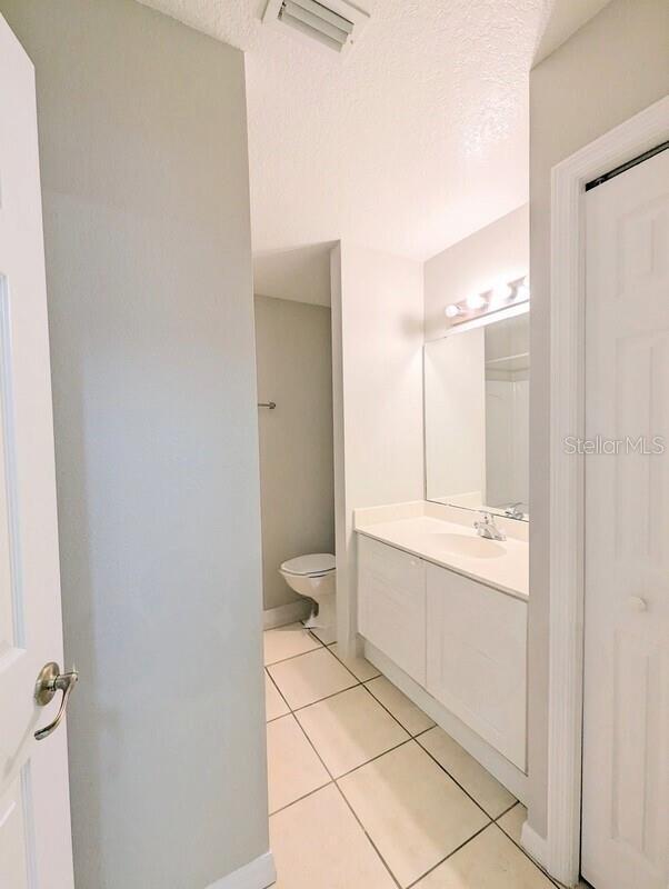 2816 Club Cortile Cir Unit A, Kissimmee, FL 34746 - full bathroom with tile patterned floors, vanity, and a textured ceiling
