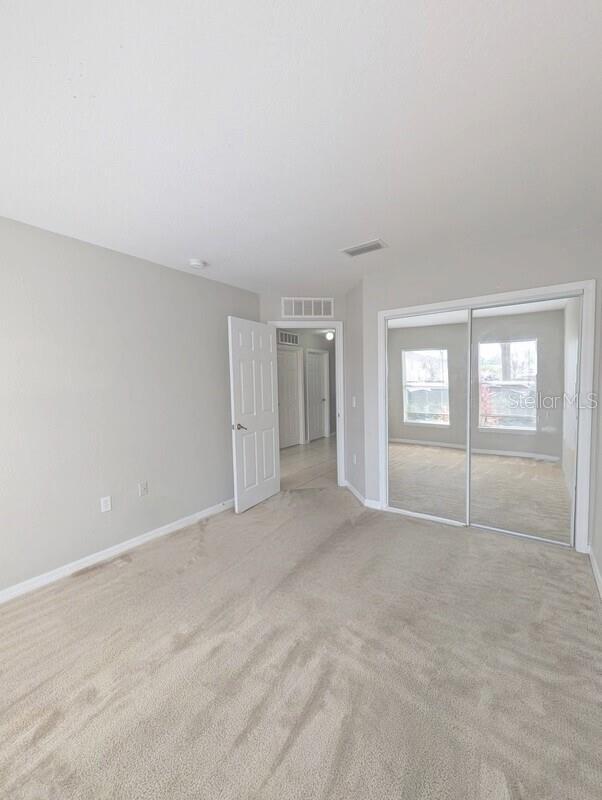 2816 Club Cortile Cir Unit A, Kissimmee, FL 34746 - unfurnished bedroom with light colored carpet and a closet