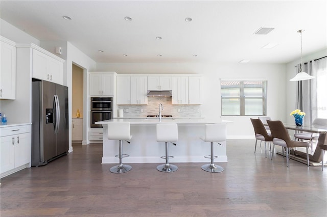 10427 Royal Cypress Way, Orlando, FL 32836 - kitchen with stainless steel appliances, under cabinet range hood, dark wood-style floors, a breakfast bar area, and recessed lighting