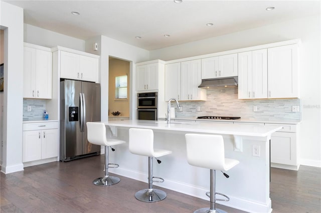 10427 Royal Cypress Way, Orlando, FL 32836 - kitchen featuring appliances with stainless steel finishes, under cabinet range hood, dark wood-style flooring, decorative backsplash, and recessed lighting