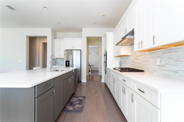 10427 Royal Cypress Way, Orlando, FL 32836 - kitchen with appliances with stainless steel finishes, under cabinet range hood, decorative backsplash, dark wood-style flooring, and light countertops