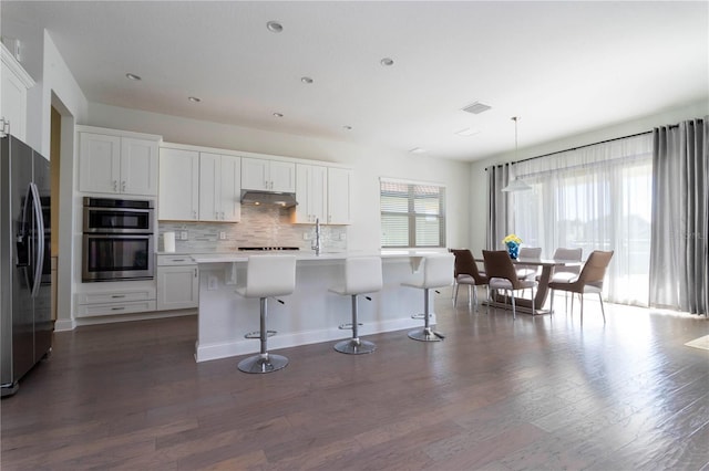 10427 Royal Cypress Way, Orlando, FL 32836 - kitchen featuring appliances with stainless steel finishes, dark wood-style floors, backsplash, light countertops, and under cabinet range hood