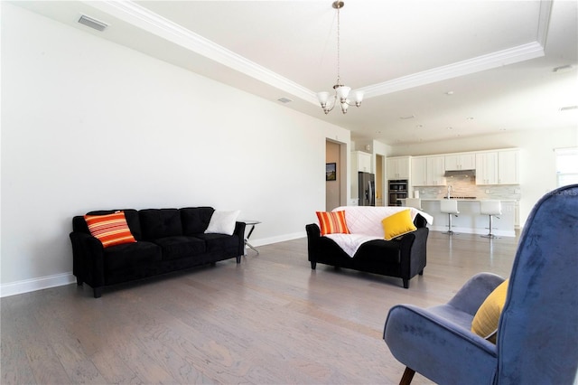 10427 Royal Cypress Way, Orlando, FL 32836 - living area with ornamental molding, a raised ceiling, light wood-style floors, and a chandelier