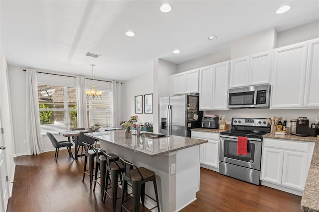 11686 Water Run Aly, Windermere, FL 34786 - kitchen featuring appliances with stainless steel finishes, white cabinetry, light stone countertops, a kitchen island with sink, and dark wood-style floors