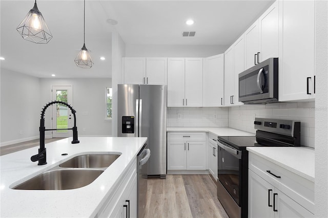 4447 Heyward St, North Port, FL 34291 - kitchen with appliances with stainless steel finishes, light wood-style floors, white cabinets, decorative light fixtures, and recessed lighting