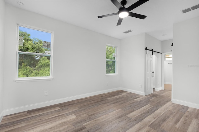 4447 Heyward St, North Port, FL 34291 - unfurnished bedroom with a barn door, wood finished floors, and ceiling fan