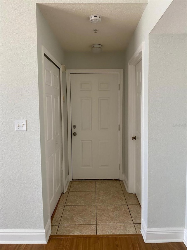 hallway featuring tile patterned floors and a textured wall