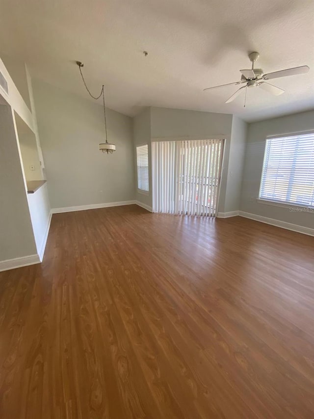 unfurnished living room featuring dark wood-type flooring and ceiling fan