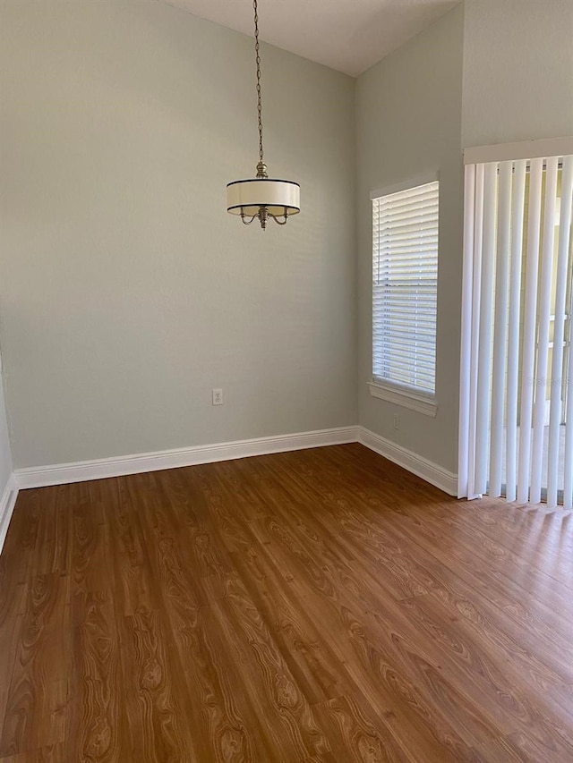 empty room featuring a chandelier and dark wood-type flooring