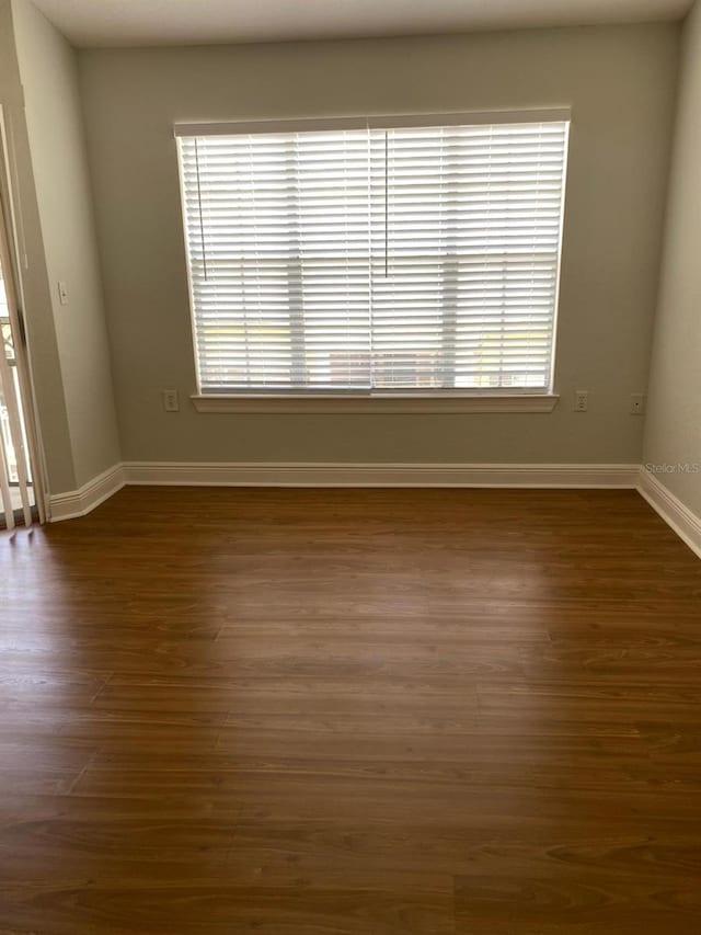 unfurnished room featuring healthy amount of natural light and dark wood finished floors