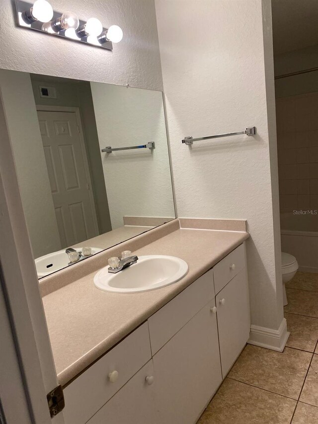 bathroom with vanity, tile patterned flooring, and a textured wall