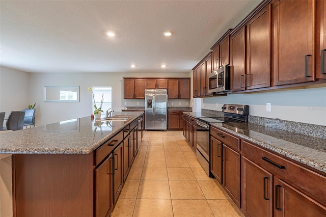 565 Ogelthorpe Dr, Davenport, FL 33897 - kitchen featuring stainless steel appliances, a center island with sink, light tile patterned floors, recessed lighting, and dark stone countertops