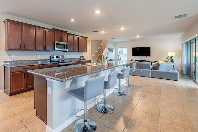 565 Ogelthorpe Dr, Davenport, FL 33897 - kitchen featuring appliances with stainless steel finishes, a kitchen breakfast bar, dark stone countertops, recessed lighting, and light tile patterned floors