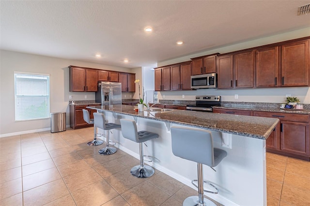 565 Ogelthorpe Dr, Davenport, FL 33897 - kitchen featuring appliances with stainless steel finishes, a kitchen bar, light tile patterned floors, dark stone countertops, and recessed lighting