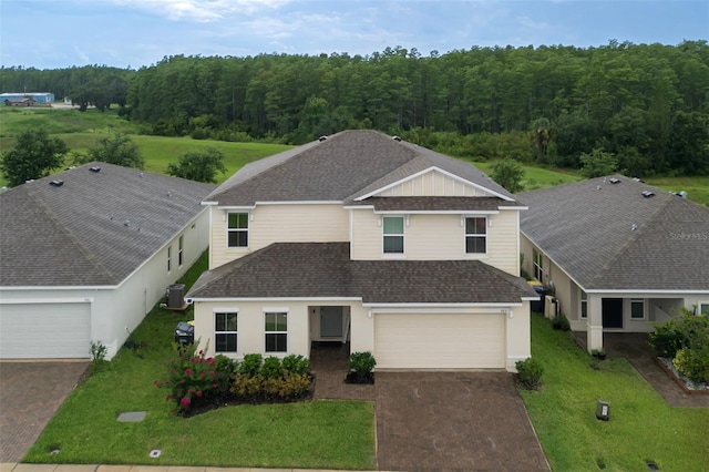 565 Ogelthorpe Dr, Davenport, FL 33897 - view of front of home featuring decorative driveway, stucco siding, roof with shingles, a front lawn, and a forest view