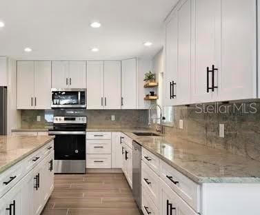 213 W Tilden St, Winter Garden, FL 34787 - kitchen featuring appliances with stainless steel finishes, recessed lighting, white cabinets, light stone counters, and light wood-style flooring