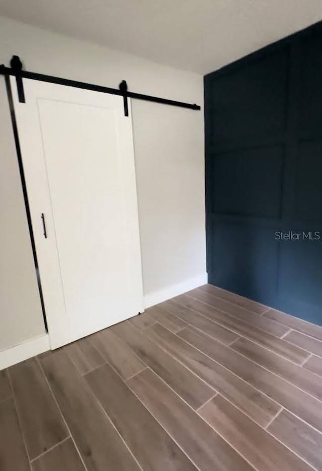 213 W Tilden St, Winter Garden, FL 34787 - unfurnished bedroom with a barn door and wood finish floors