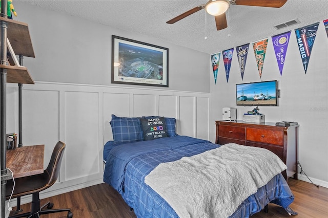 2980 Cool Breeze Cir, Saint Cloud, FL 34769 - bedroom with wood finished floors, a textured ceiling, wainscoting, a decorative wall, and a ceiling fan