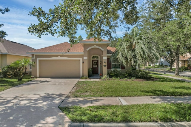 215 Foxglove Way, Deland, FL 32724 - mediterranean / spanish-style house featuring stucco siding, a garage, a front lawn, concrete driveway, and a shingled roof
