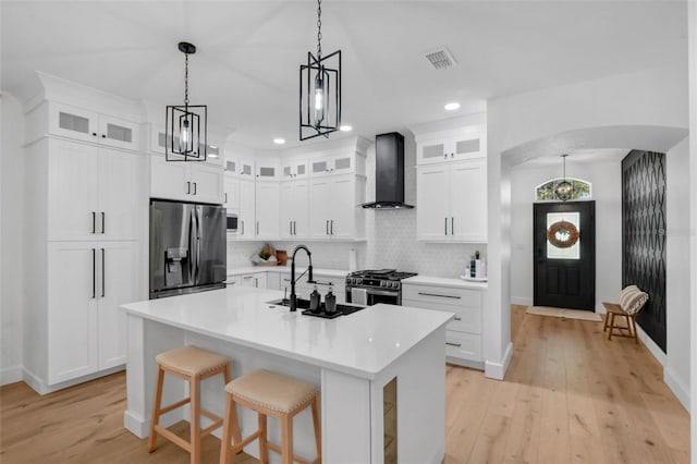 215 Foxglove Way, Deland, FL 32724 - kitchen with stainless steel appliances, wall chimney exhaust hood, arched walkways, light wood-style flooring, and recessed lighting