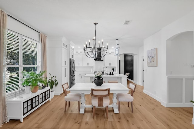 215 Foxglove Way, Deland, FL 32724 - dining area with a chandelier, arched walkways, and light wood-type flooring