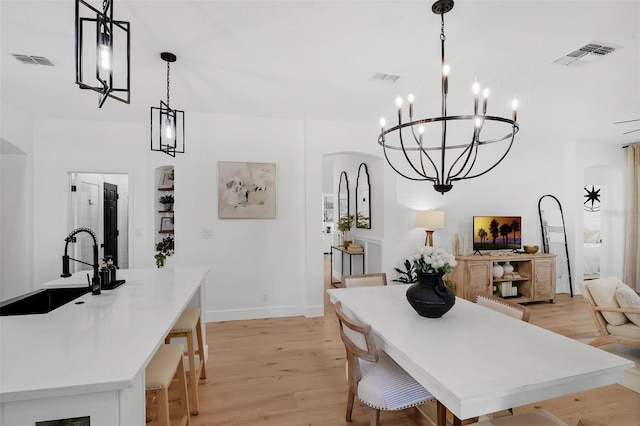 215 Foxglove Way, Deland, FL 32724 - dining room featuring light wood-style flooring, a chandelier, and arched walkways