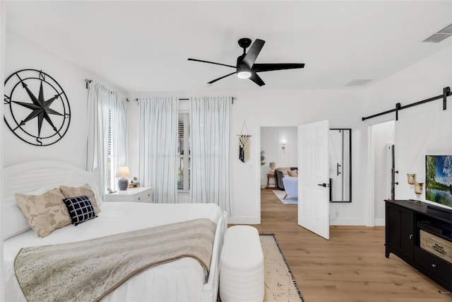 215 Foxglove Way, Deland, FL 32724 - bedroom featuring a barn door, light wood-style flooring, and a ceiling fan