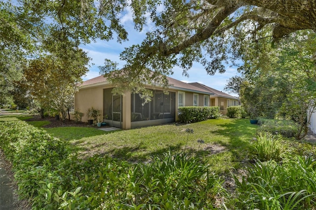 215 Foxglove Way, Deland, FL 32724 - view of side of home featuring a lawn, stucco siding, and a sunroom