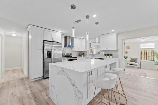 2075 Abalone Ave, Indialantic, FL 32903 - kitchen featuring stainless steel appliances, wall chimney range hood, light wood-style flooring, tasteful backsplash, and a kitchen island
