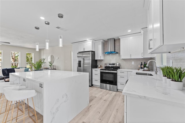 2075 Abalone Ave, Indialantic, FL 32903 - kitchen with appliances with stainless steel finishes, wall chimney range hood, decorative backsplash, light wood-style flooring, and white cabinets