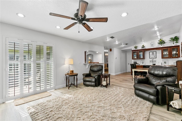 4230 Havana Dr, Cocoa, FL 32927 - living area featuring light wood-style flooring, a ceiling fan, lofted ceiling, a textured ceiling, and arched walkways