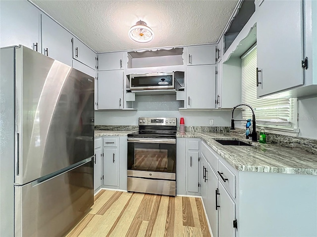 207 Kay St, Auburndale, FL 33823 - kitchen with stainless steel appliances, light wood-style flooring, and a textured ceiling