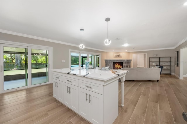 102 Linda Ln, Lake Mary, FL 32746 - kitchen with a fireplace, light wood-type flooring, white cabinetry, crown molding, and a kitchen island