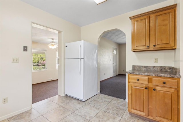 146 Mills Rd, Deland, FL 32724 - kitchen with freestanding refrigerator, light carpet, arched walkways, and dark countertops