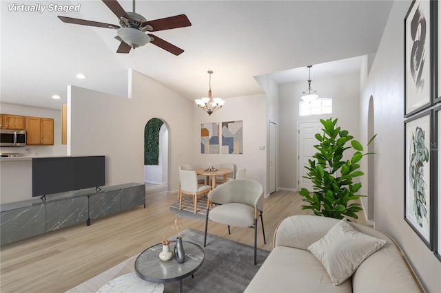 16603 Corner Lake Dr, Orlando, FL 32820 - living room with arched walkways, a chandelier, light wood-style floors, vaulted ceiling, and ceiling fan