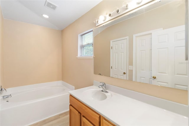16603 Corner Lake Dr, Orlando, FL 32820 - full bath featuring a garden tub, vanity, vaulted ceiling, and wood finished floors