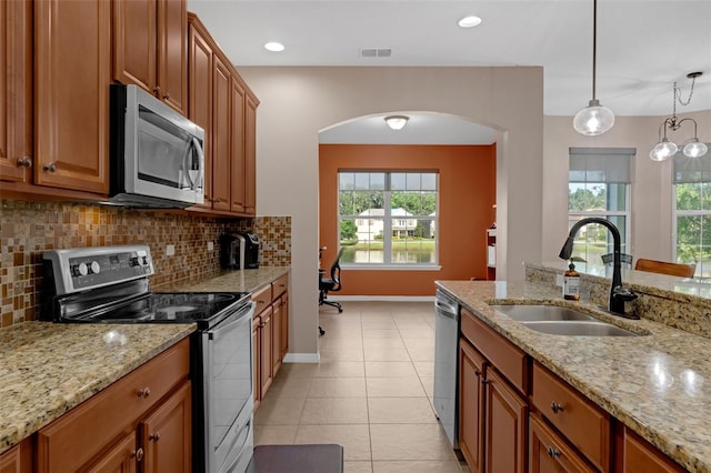 480 Buckhorn Dr, Winter Springs, FL 32708 - kitchen with stainless steel appliances, brown cabinets, arched walkways, decorative backsplash, and healthy amount of natural light