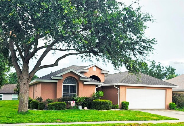 4471 Treasure Cay Rd, Tavares, FL 32778 - view of front of home featuring an attached garage, a front yard, stucco siding, driveway, and roof with shingles