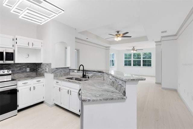 3280 Soho St Unit 306, Orlando, FL 32835 - kitchen with appliances with stainless steel finishes, a peninsula, light wood-style floors, a tray ceiling, and light stone countertops